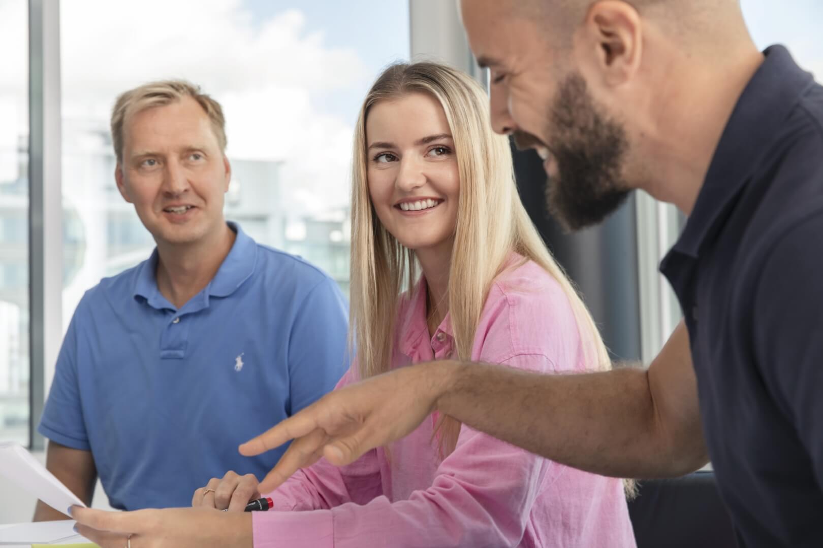 three people discussing documents with smiles on thier faces